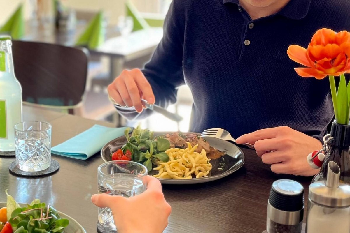 Ein Ausschnitt von einem Tisch mit Speisen, die von zwei Personen gegessen werden