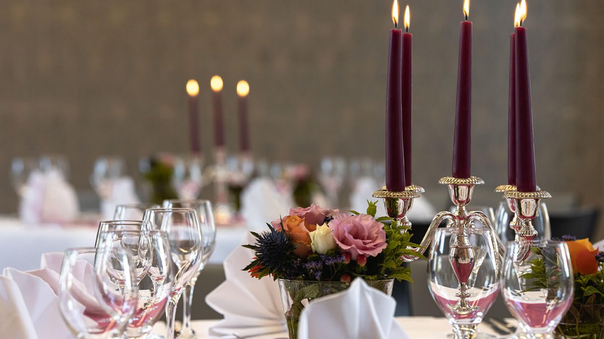 Festlich gedeckter Tisch mit Blumen und violetten Kerzen 
