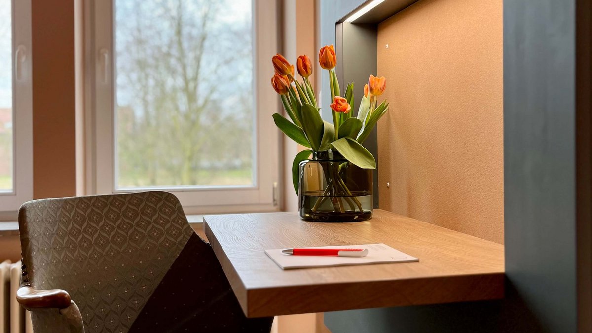 Indirekt beleuchteter Schreibtisch mit Sessel und Tulpen 
