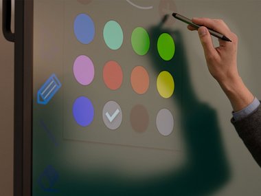 Eine Hand zeigt mit einem Stift auf einen interaktiven Bildschirm