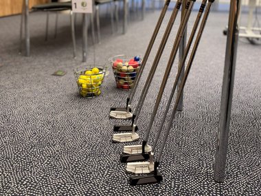 Golfschläger an einen Tagungstisch gelehnt für Bürogolf