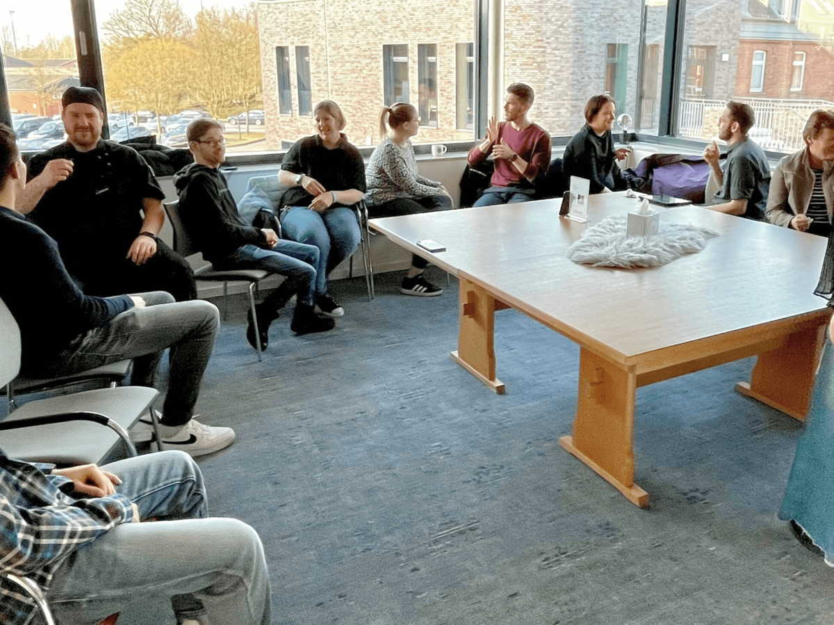Eine Gruppe sitzt im Stuhlkreis und übt Gebärdensprache