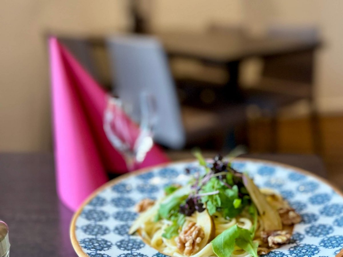 Spagetti Gorgonzola auf einem blau-buntem Teller mit Gabel und Weinglas in abendlicher Atmosphäre