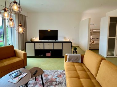 Wohnzimmer mit gelben Sofas und TV Board 
