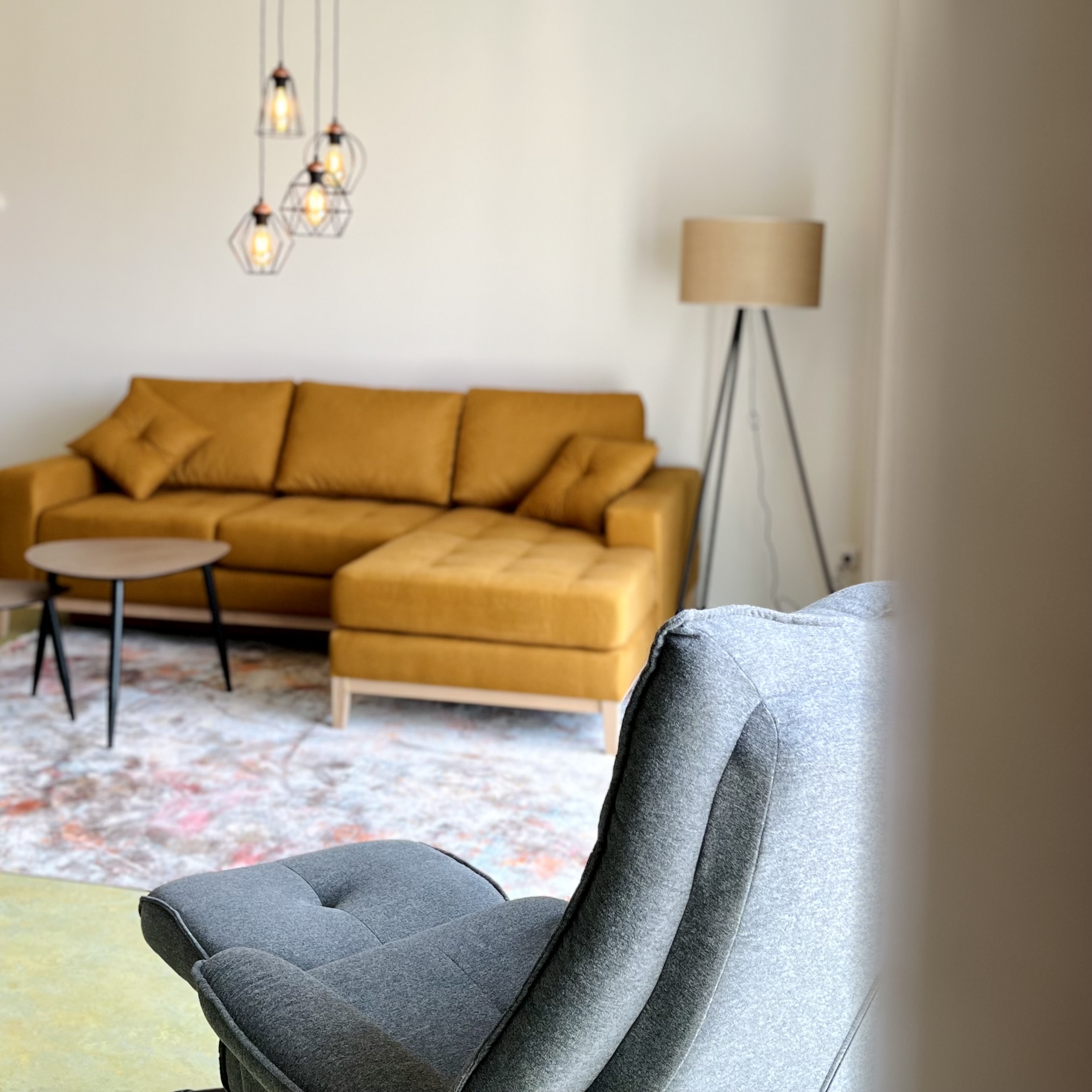 Wohnzimmer mit grauem Sessel und gelben Sofa